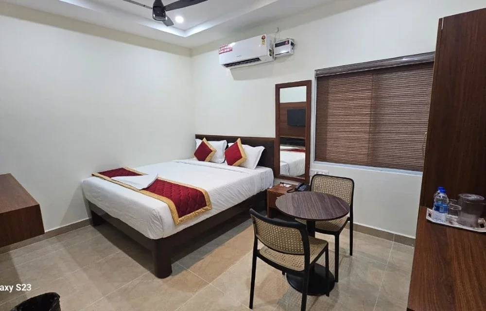 Wide view of a double-bed guest room with a round seating table