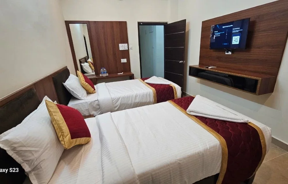 Twin beds facing a wall-mounted television in a guest room