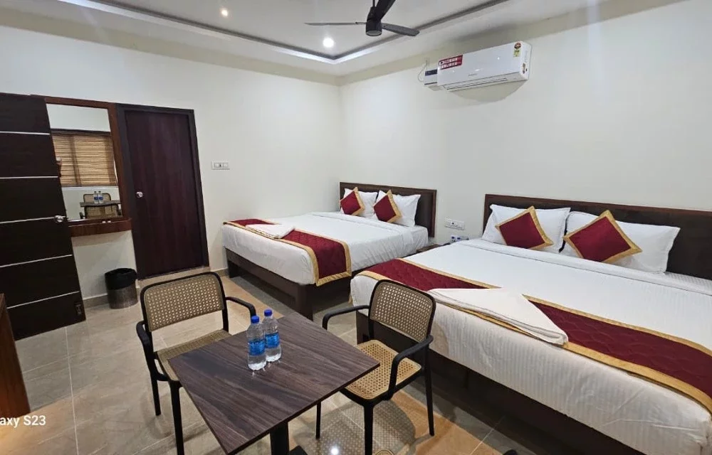 Larger guest room with two double beds and a central seating table